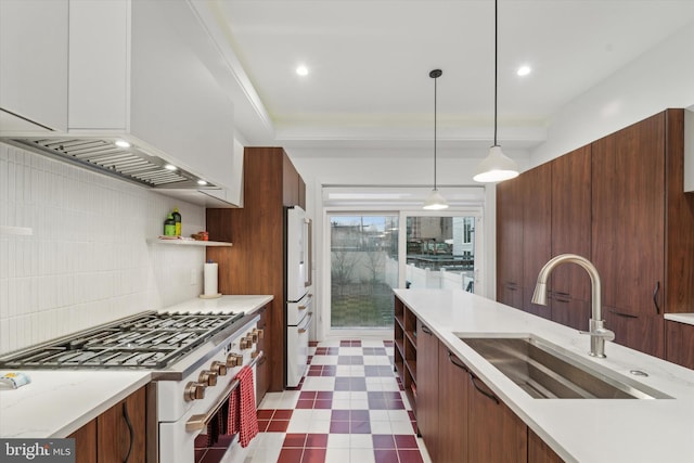 kitchen with sink, white refrigerator, tasteful backsplash, stainless steel range, and decorative light fixtures