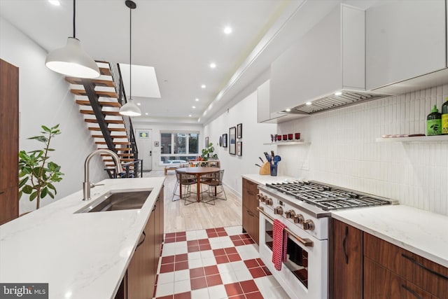 kitchen featuring decorative light fixtures, tasteful backsplash, sink, high end white range oven, and light stone counters