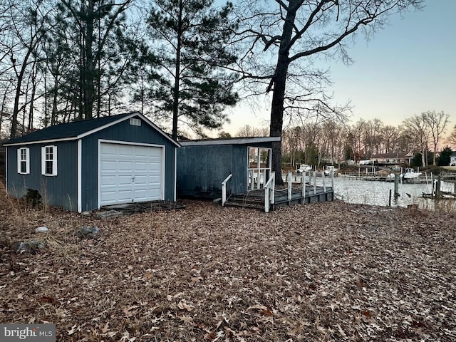 exterior space with a garage, a water view, and an outbuilding