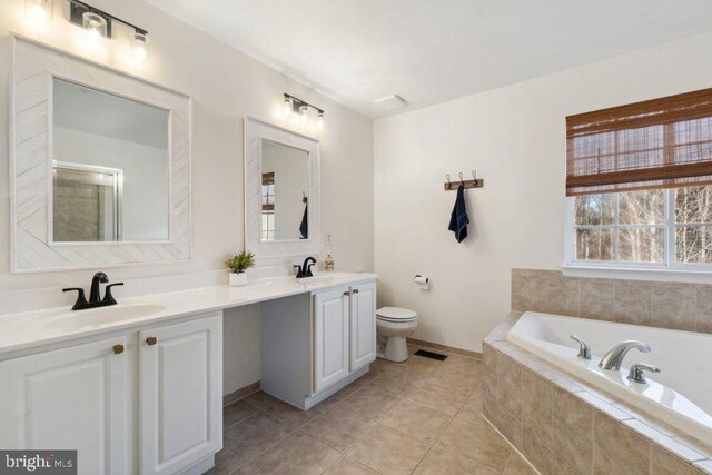 bathroom featuring tile patterned flooring, vanity, tiled bath, and toilet