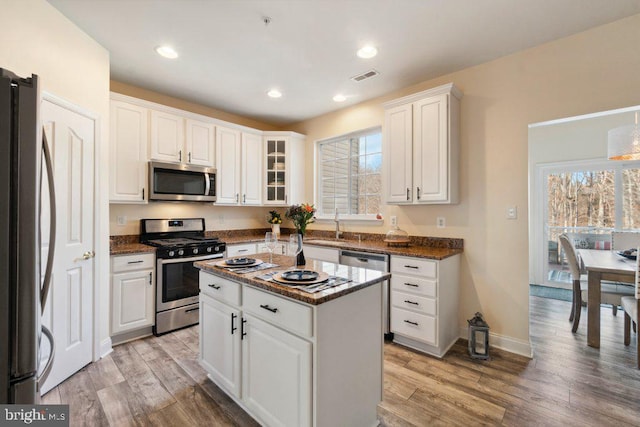 kitchen featuring white cabinetry, stainless steel appliances, a center island, and light hardwood / wood-style floors