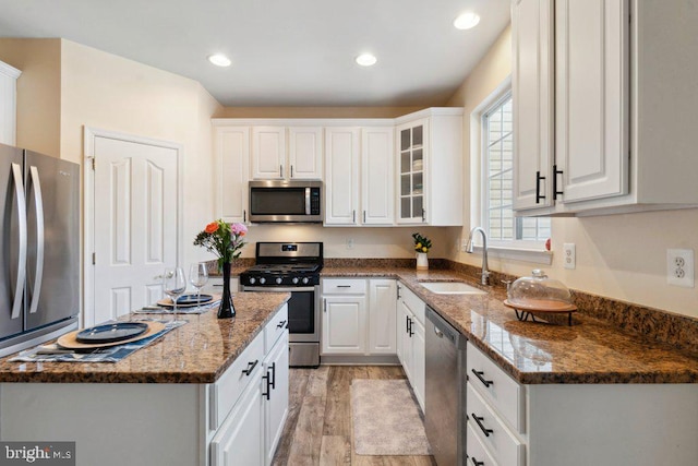 kitchen featuring stainless steel appliances, white cabinetry, sink, and dark stone countertops