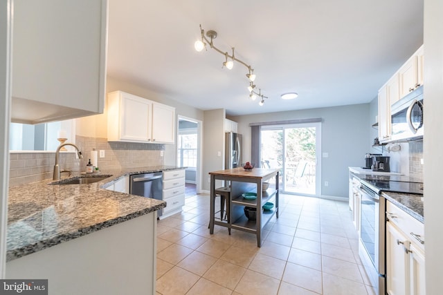 kitchen with light tile patterned floors, appliances with stainless steel finishes, sink, and white cabinets