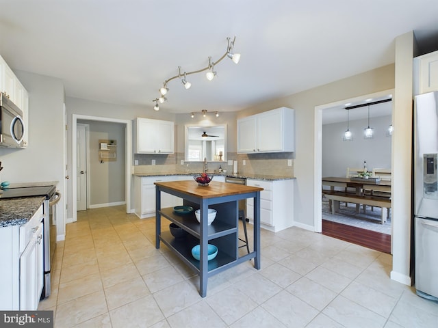 kitchen featuring sink, backsplash, stainless steel appliances, white cabinets, and dark stone counters