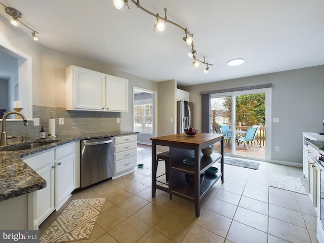 kitchen featuring white cabinetry, appliances with stainless steel finishes, sink, and dark stone counters