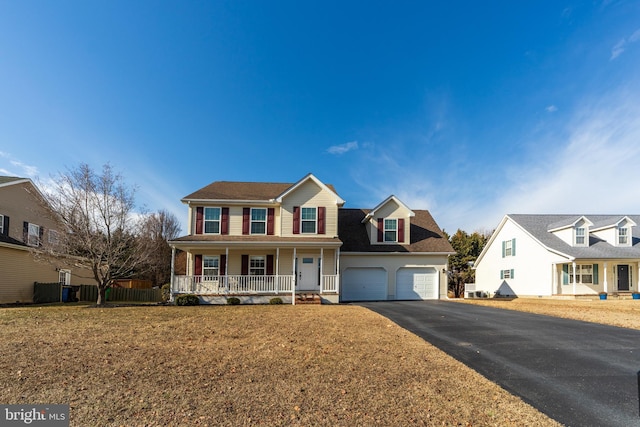 view of front of property featuring a garage, covered porch, and a front lawn