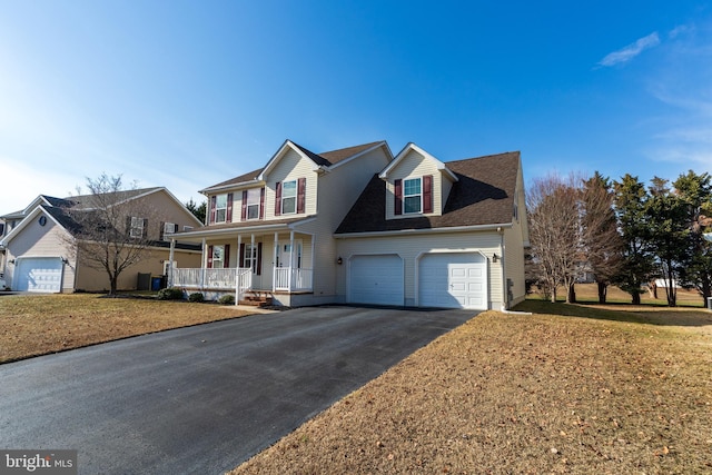 view of front of house with a garage, a front lawn, and covered porch