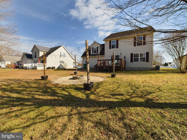 back of property featuring a deck, a lawn, and an outdoor fire pit