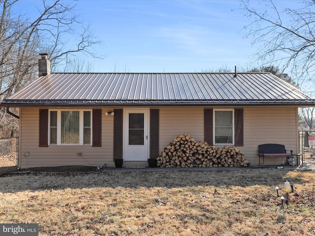 view of front of home featuring a chimney, fence, metal roof, and a front yard