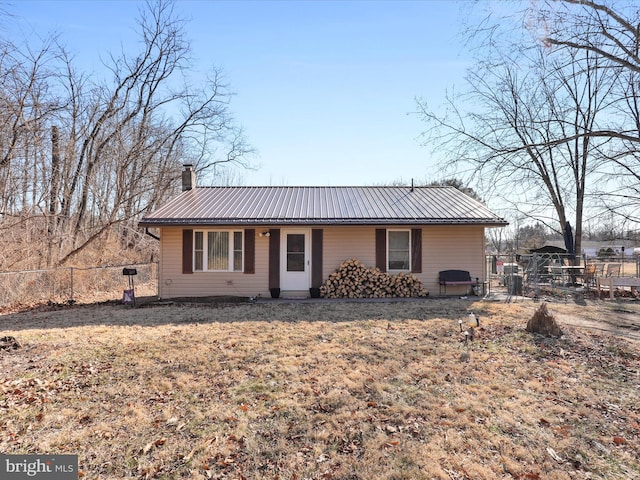 view of front of property featuring metal roof, fence, and a chimney