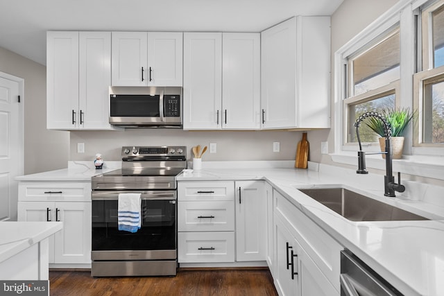 kitchen featuring stainless steel appliances, light stone countertops, sink, and white cabinets