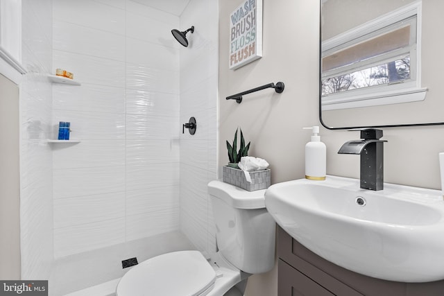 bathroom with vanity, tiled shower, and toilet