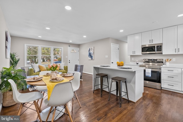 kitchen with a kitchen island, appliances with stainless steel finishes, white cabinets, and dark hardwood / wood-style flooring