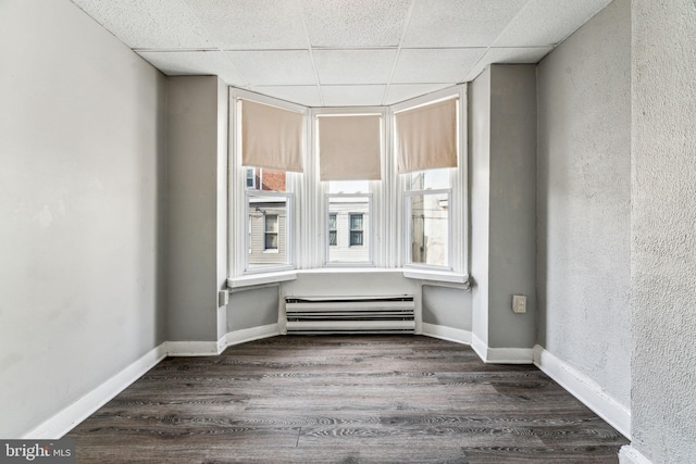 spare room featuring a paneled ceiling and dark hardwood / wood-style floors