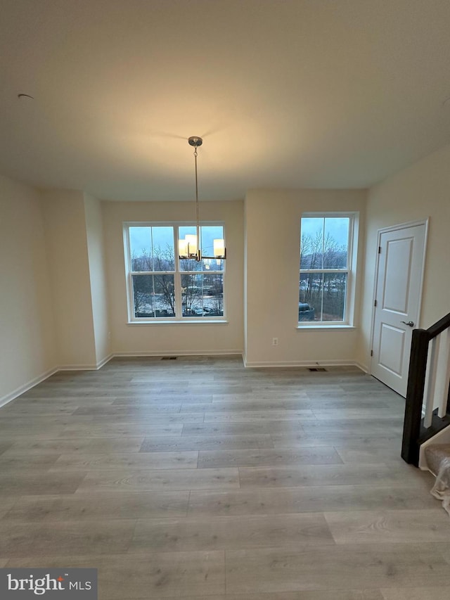 unfurnished dining area featuring a notable chandelier, a wealth of natural light, and light hardwood / wood-style floors