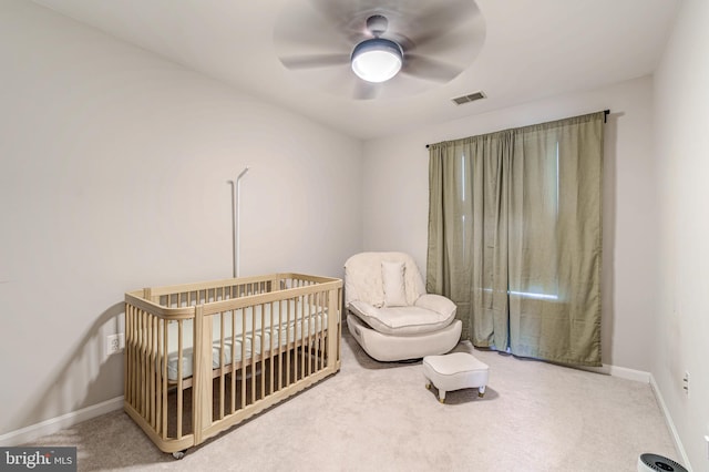 bedroom featuring a crib, carpet, and ceiling fan