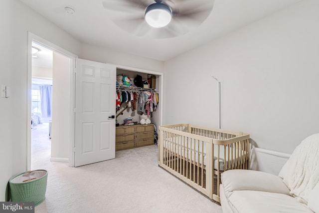 carpeted bedroom with a crib, a closet, and ceiling fan