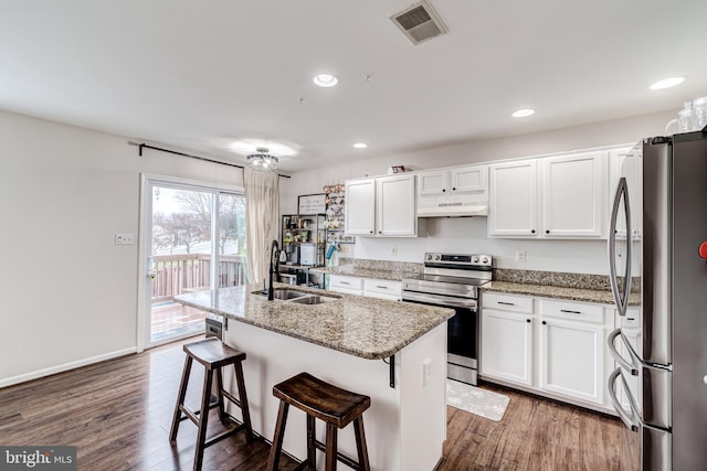 kitchen with sink, stone counters, white cabinetry, appliances with stainless steel finishes, and a center island with sink