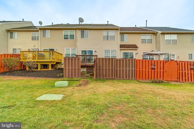 rear view of house featuring a wooden deck and a yard