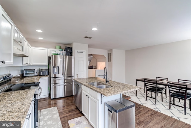 kitchen with white cabinetry, sink, stainless steel appliances, and an island with sink