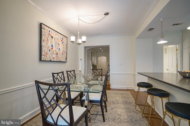 dining space featuring ornamental molding, a chandelier, and dark hardwood / wood-style flooring