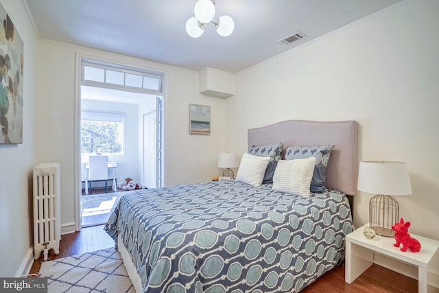 bedroom with hardwood / wood-style floors, crown molding, and radiator heating unit