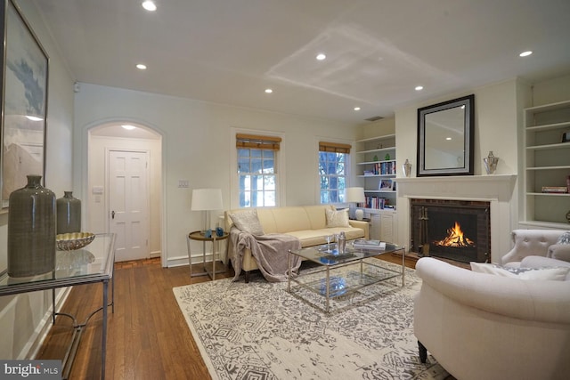 living room featuring built in shelves and dark hardwood / wood-style floors