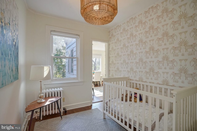 bedroom featuring crown molding, radiator heating unit, and wood-type flooring