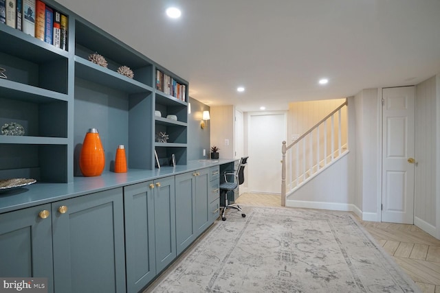 home office with built in shelves, built in desk, and light parquet floors