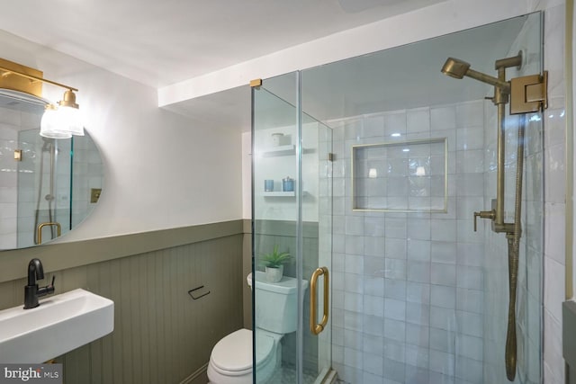 bathroom featuring sink, a shower with door, and toilet