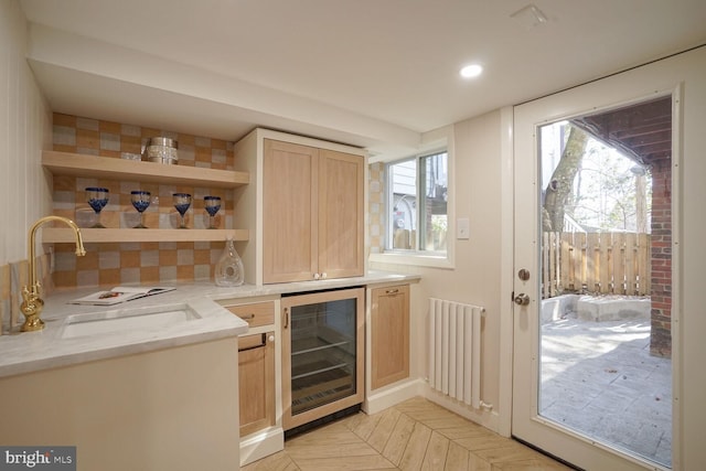 bar with radiator, light brown cabinetry, sink, wine cooler, and light parquet floors