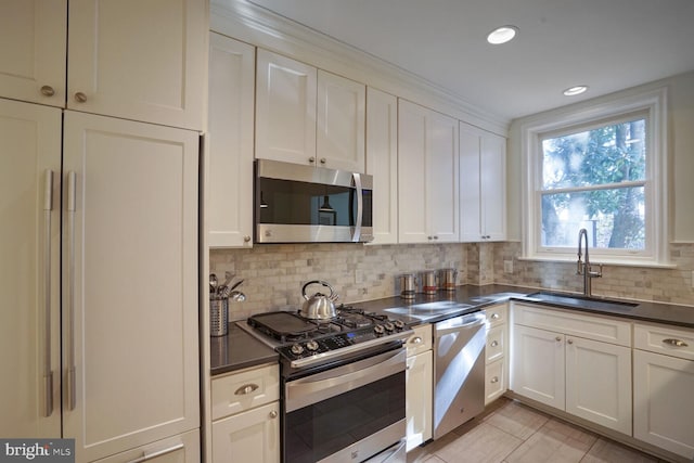 kitchen featuring tasteful backsplash, sink, white cabinets, and appliances with stainless steel finishes