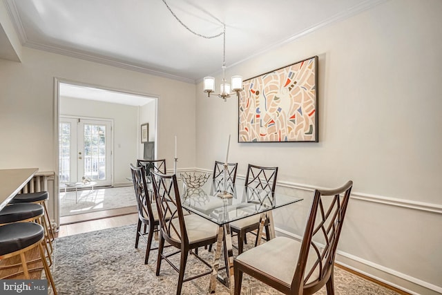 dining area featuring hardwood / wood-style flooring, ornamental molding, a chandelier, and french doors