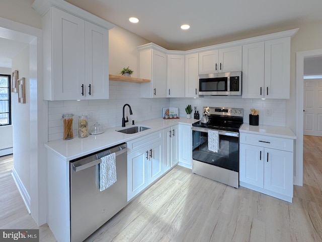 kitchen featuring stainless steel appliances, white cabinetry, sink, and light wood-type flooring