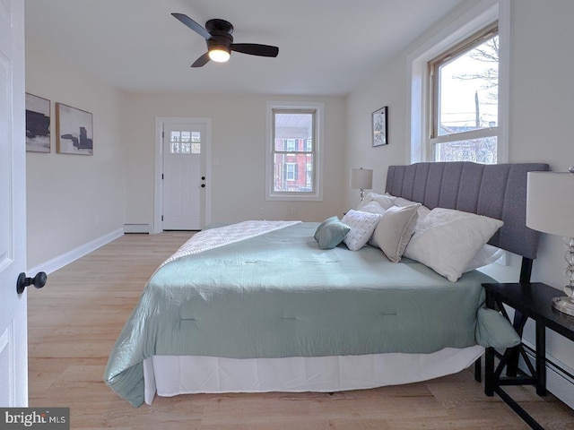 bedroom with ceiling fan, a baseboard radiator, and light hardwood / wood-style flooring