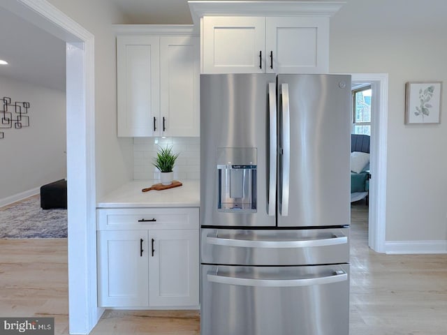 kitchen featuring stainless steel refrigerator with ice dispenser, light wood-type flooring, and white cabinets