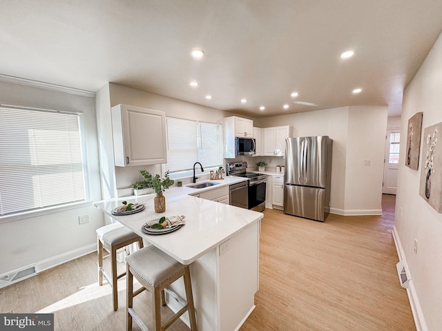 kitchen with white cabinetry, appliances with stainless steel finishes, a breakfast bar, and sink