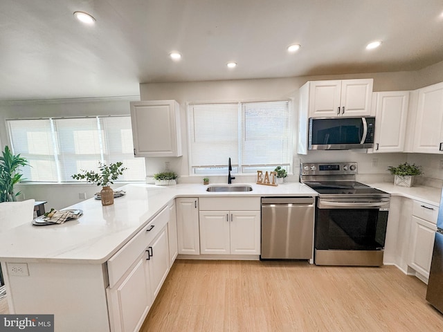 kitchen featuring sink, appliances with stainless steel finishes, white cabinetry, a healthy amount of sunlight, and light wood-type flooring