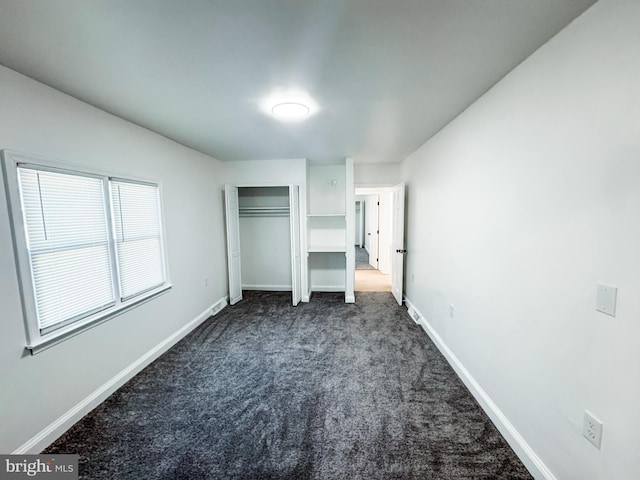 unfurnished bedroom with a closet and dark colored carpet