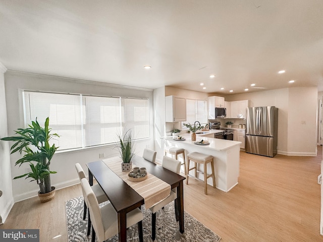 dining space with sink and light wood-type flooring