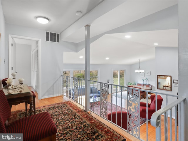 corridor with wood-type flooring, vaulted ceiling, and a chandelier