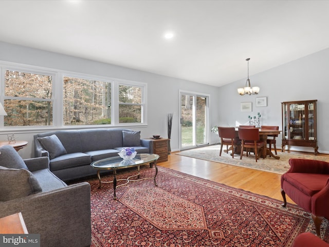 living room with vaulted ceiling, hardwood / wood-style floors, and a notable chandelier