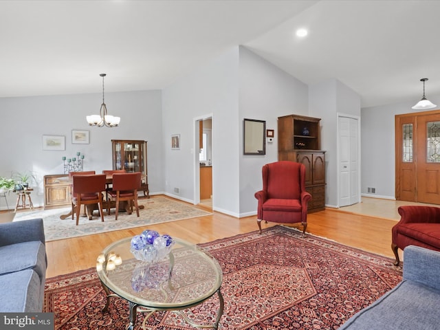 living room featuring an inviting chandelier, high vaulted ceiling, and light wood-type flooring