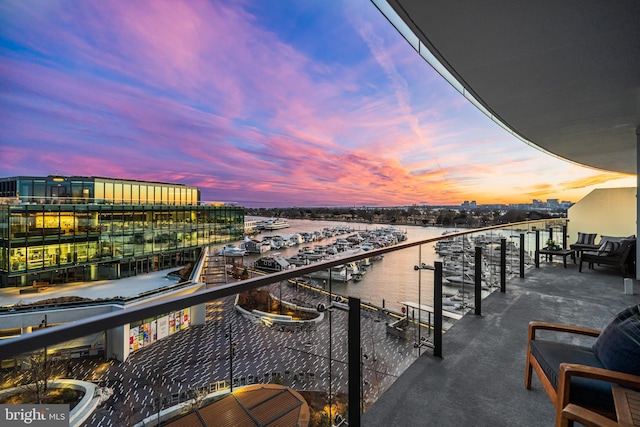 balcony at dusk featuring a water view