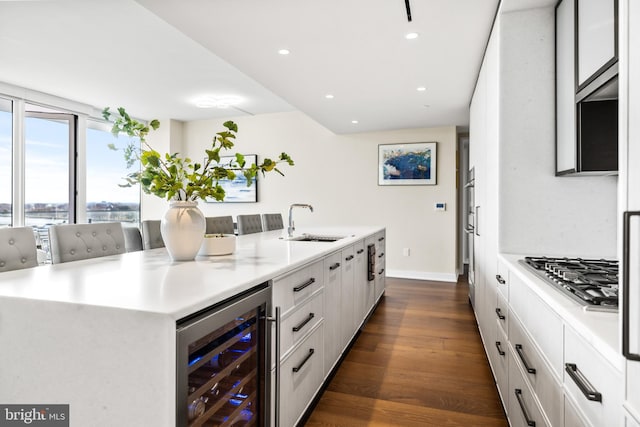 kitchen with sink, white cabinetry, a spacious island, wine cooler, and a kitchen bar