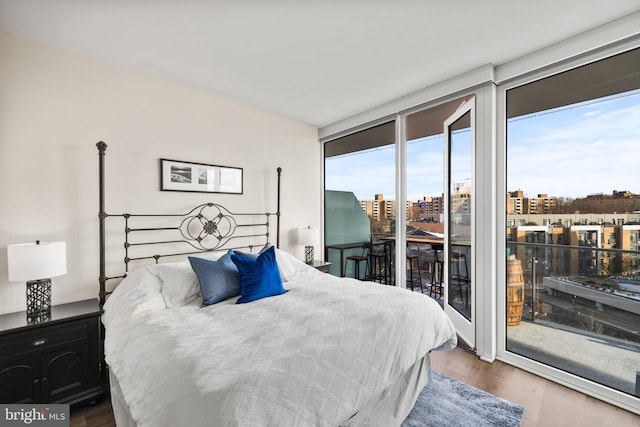 bedroom with wood-type flooring, floor to ceiling windows, and access to outside