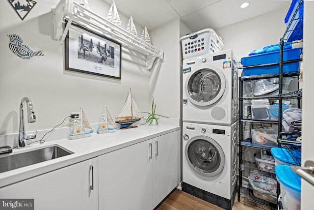 laundry area with cabinets, stacked washer / drying machine, sink, and dark hardwood / wood-style flooring