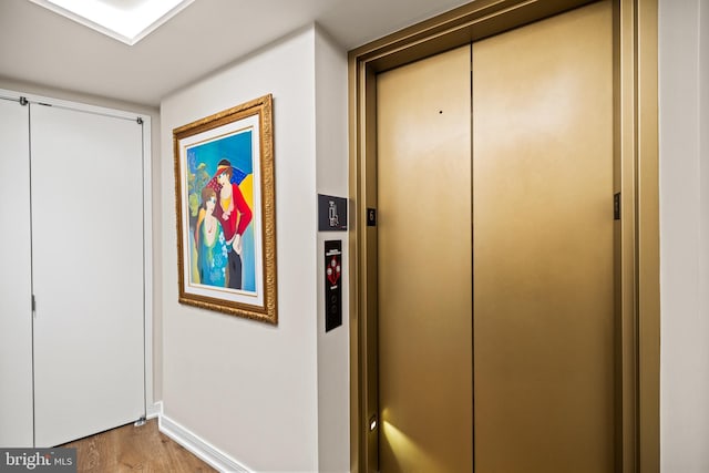 corridor with elevator and light wood-type flooring