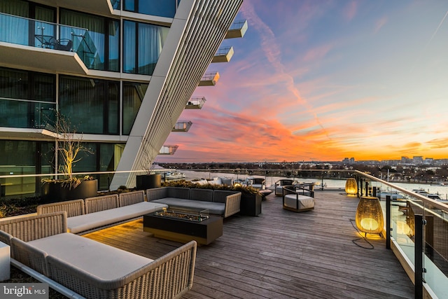 deck at dusk featuring a fire pit and a water view