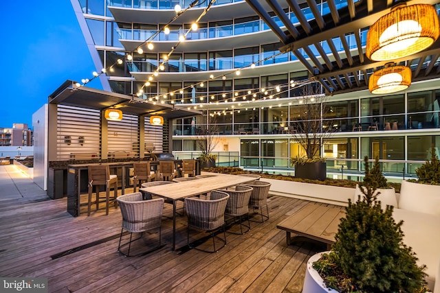 wooden deck featuring a pergola, exterior bar, and exterior kitchen